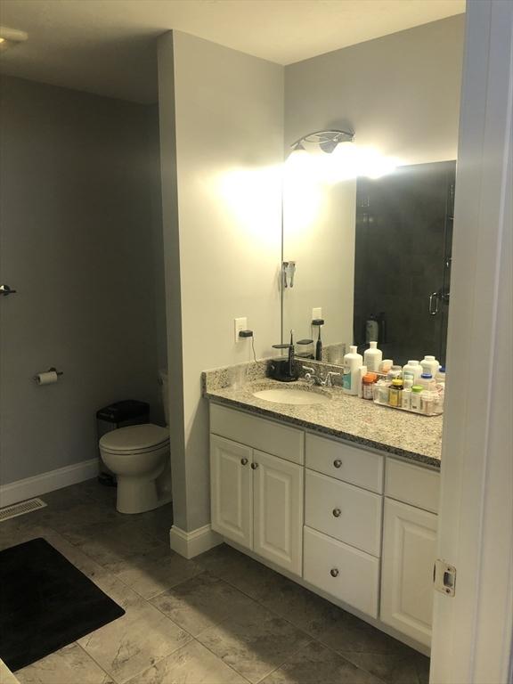 full bath with tile patterned flooring, vanity, toilet, baseboards, and a stall shower