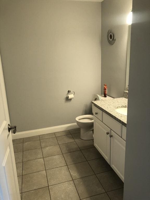 bathroom with toilet, tile patterned floors, baseboards, and vanity