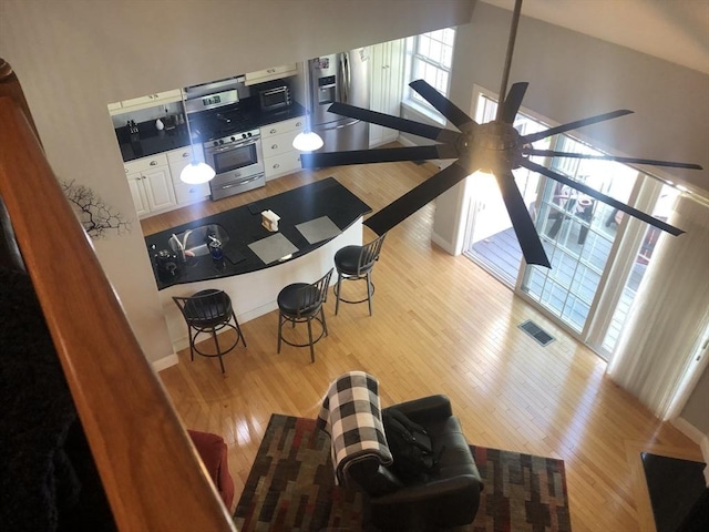 kitchen with visible vents, wood finished floors, oven, white cabinets, and a ceiling fan