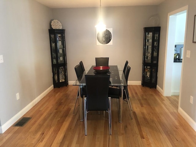 dining space with baseboards, wood finished floors, and visible vents