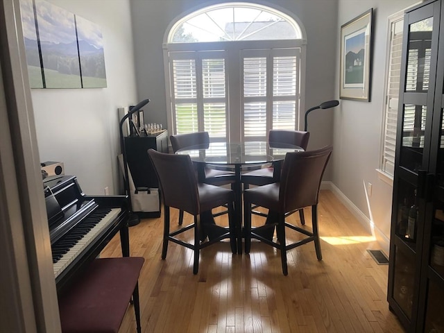 dining room featuring baseboards, light wood-style flooring, and visible vents