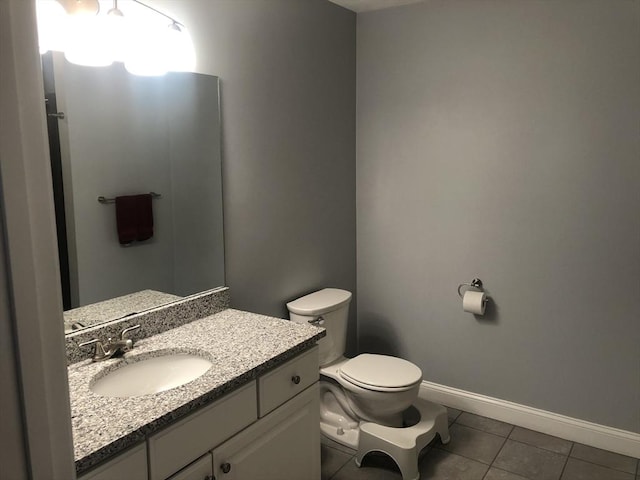 bathroom with tile patterned flooring, baseboards, toilet, and vanity