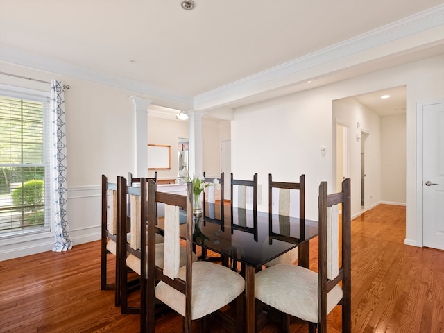 dining space featuring ornamental molding, plenty of natural light, ornate columns, and wood-type flooring