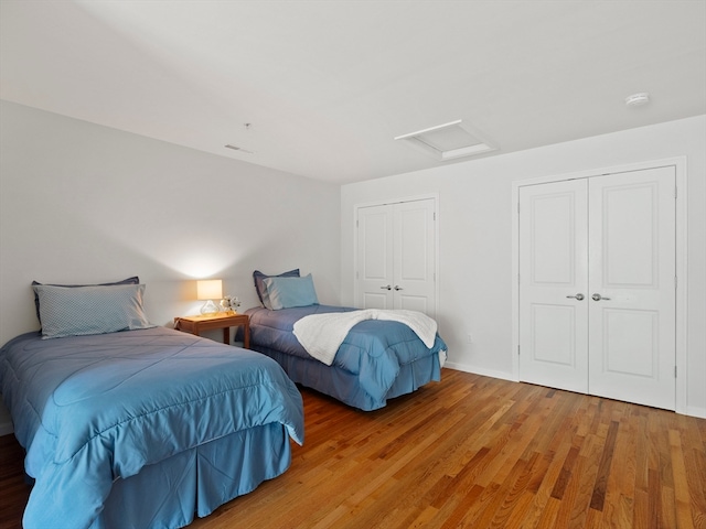 bedroom featuring hardwood / wood-style floors and two closets