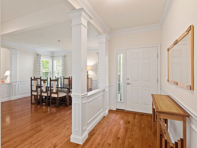 foyer entrance featuring ornamental molding, light wood-type flooring, and ornate columns