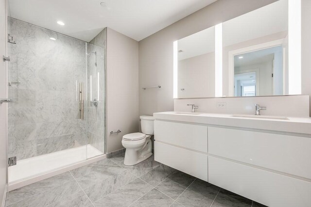 bathroom featuring a shower with door, vanity, and toilet