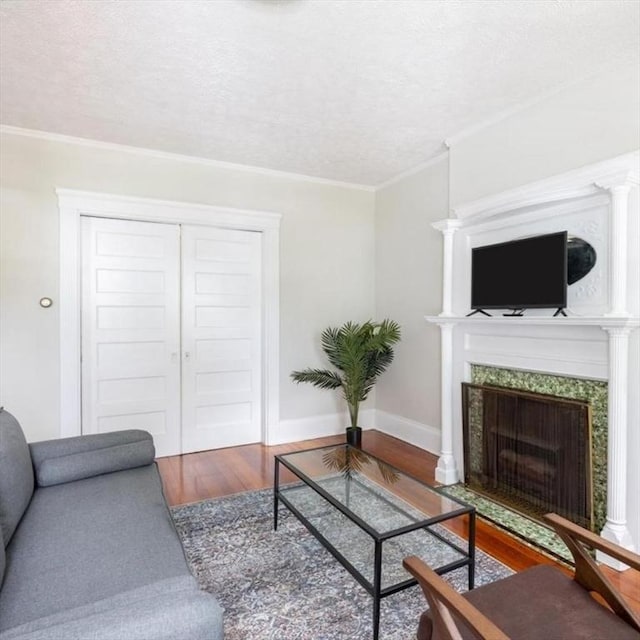 living room with a textured ceiling, ornamental molding, wood finished floors, and a high end fireplace