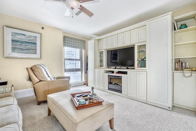 living room featuring ceiling fan, a fireplace, and light colored carpet