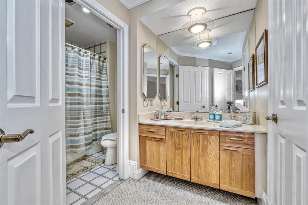 bathroom featuring vanity, tile patterned floors, a shower with curtain, toilet, and ornamental molding