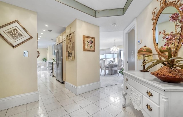 corridor featuring light tile patterned floors and an inviting chandelier