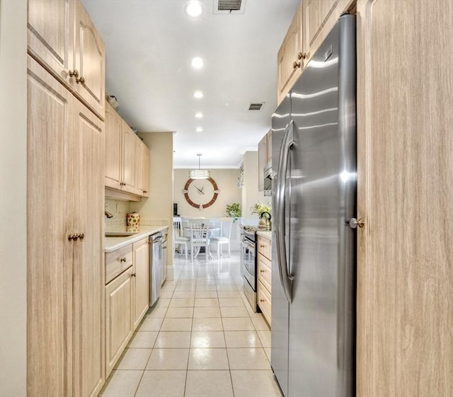 kitchen featuring light tile patterned floors, light brown cabinetry, crown molding, and appliances with stainless steel finishes