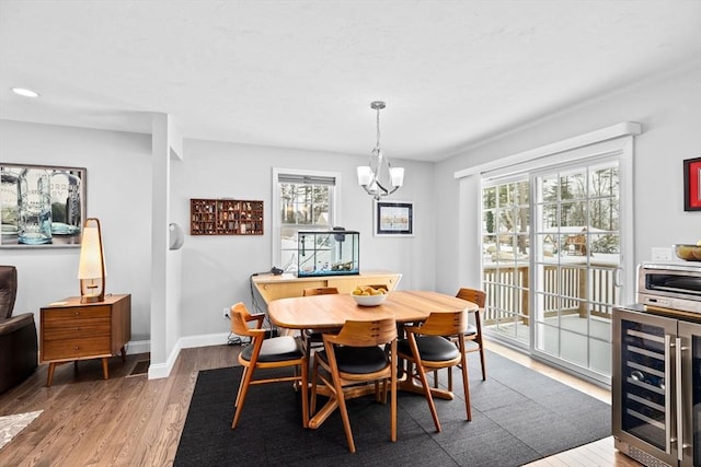 dining space with hardwood / wood-style flooring, a healthy amount of sunlight, wine cooler, and a chandelier