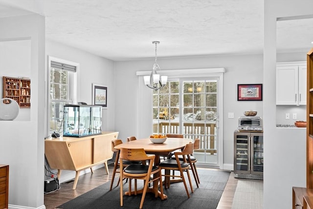 dining area with wine cooler, hardwood / wood-style floors, a notable chandelier, and a textured ceiling