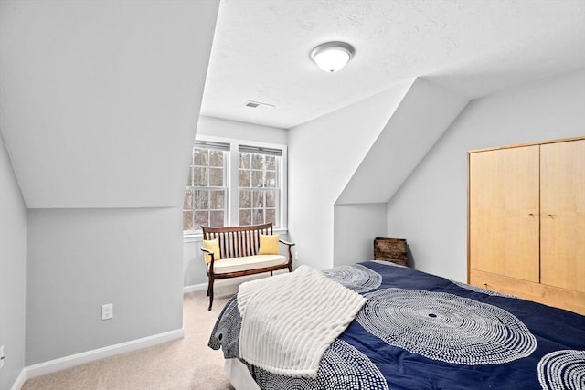 carpeted bedroom featuring lofted ceiling and a textured ceiling