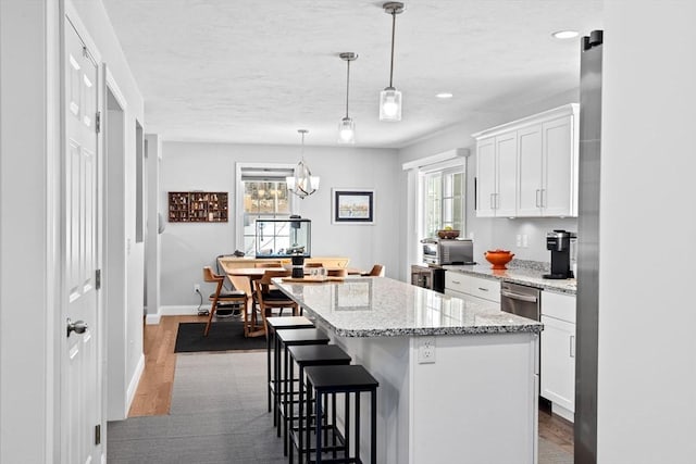 kitchen featuring a breakfast bar area, a center island, a wealth of natural light, pendant lighting, and white cabinets