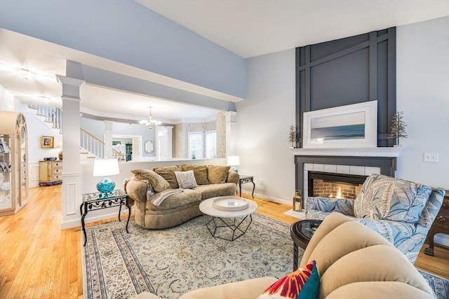 31 Fox Holw, Plymouth, MA 02360 - living area featuring light wood-type flooring, a tiled fireplace, ornate columns, a chandelier, and stairs