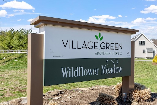 community sign with fence and a yard