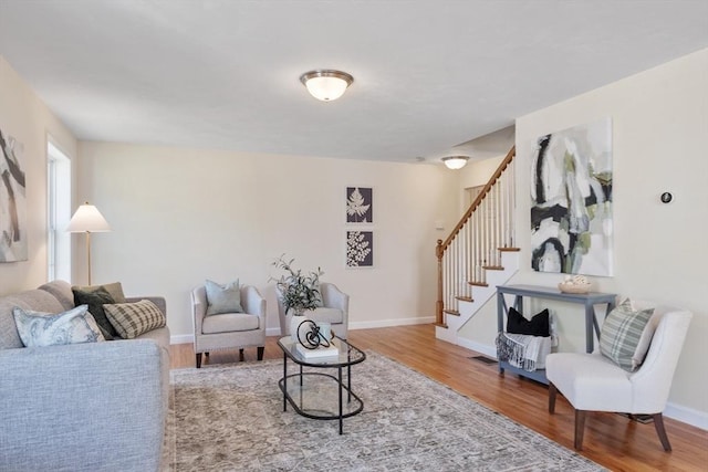 living area with baseboards, wood finished floors, and stairs