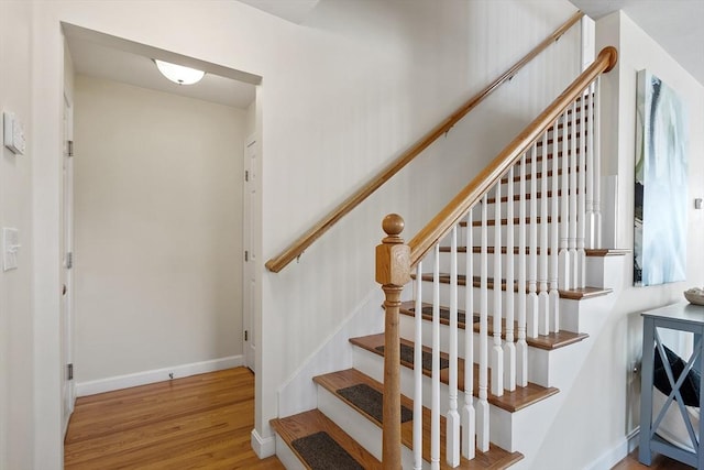 staircase featuring baseboards and wood finished floors