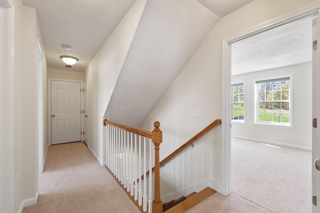 corridor with baseboards, vaulted ceiling, carpet flooring, and an upstairs landing
