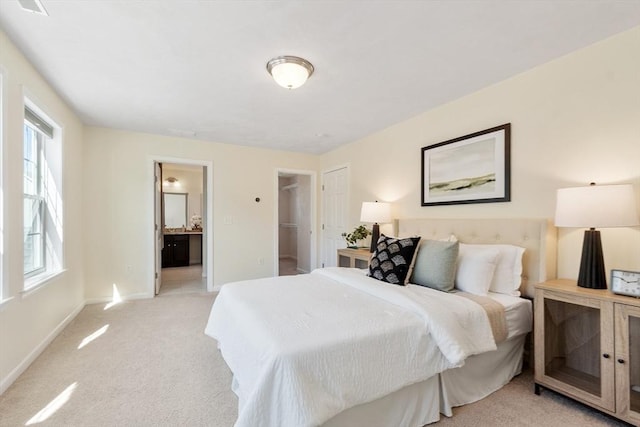 bedroom with ensuite bathroom, baseboards, light colored carpet, and multiple windows