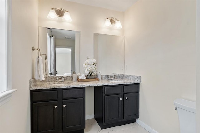 bathroom featuring marble finish floor, a sink, double vanity, and toilet
