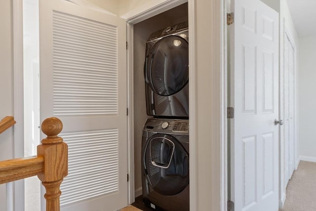 laundry room with baseboards, stacked washing maching and dryer, laundry area, and light carpet