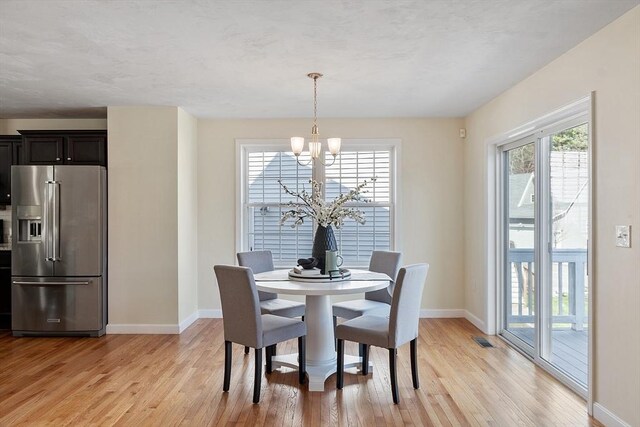 dining area with light wood-type flooring, baseboards, a notable chandelier, and visible vents