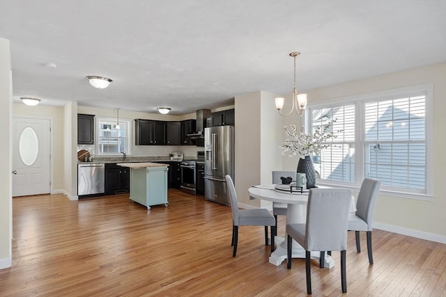 dining room featuring light wood finished floors, baseboards, and an inviting chandelier