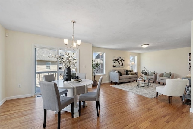 dining area with an inviting chandelier, light wood finished floors, and baseboards