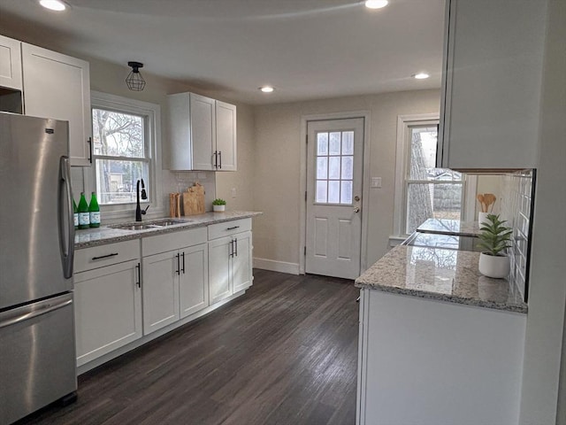 kitchen featuring light stone countertops, white cabinets, sink, stainless steel fridge, and dark hardwood / wood-style floors