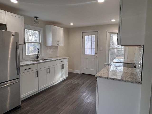 kitchen featuring stainless steel fridge, sink, backsplash, white cabinetry, and light stone counters