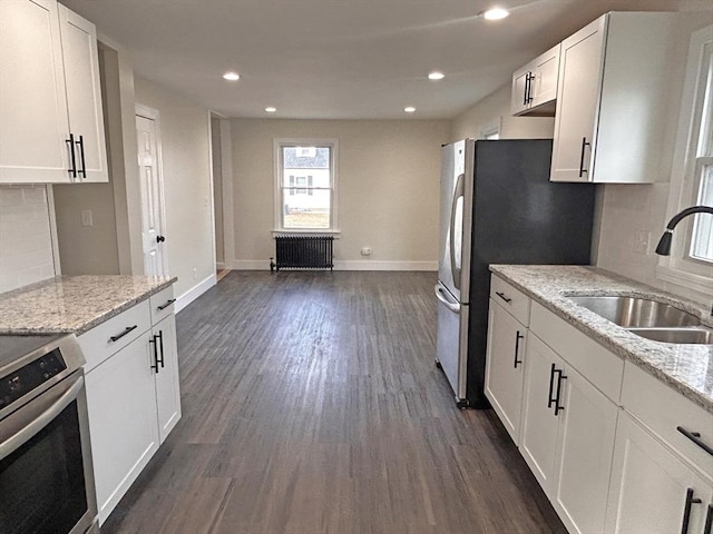 kitchen featuring sink, light stone counters, white cabinetry, and appliances with stainless steel finishes