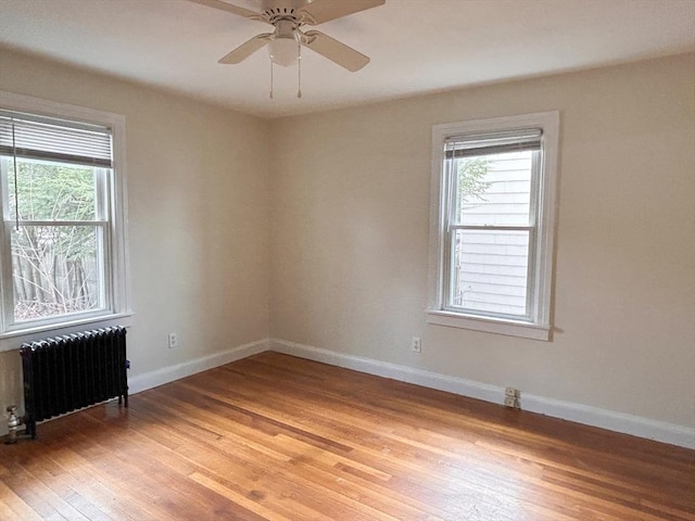 empty room with light hardwood / wood-style floors, radiator heating unit, and ceiling fan