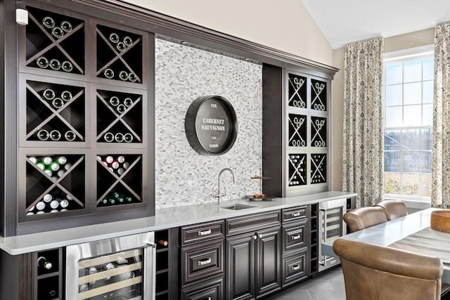 bar with indoor wet bar, lofted ceiling, wine cooler, and tasteful backsplash