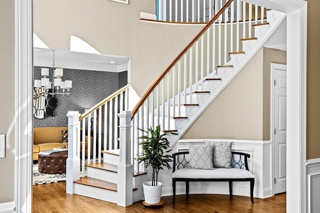 stairs featuring a chandelier, an accent wall, and wood finished floors