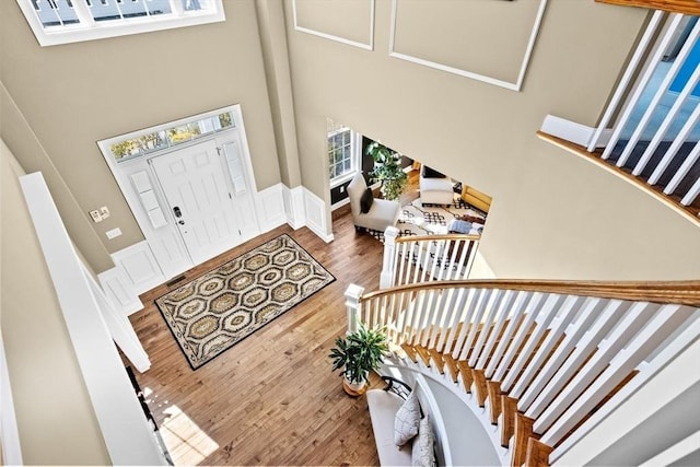 entryway with stairway, a high ceiling, wood finished floors, and wainscoting