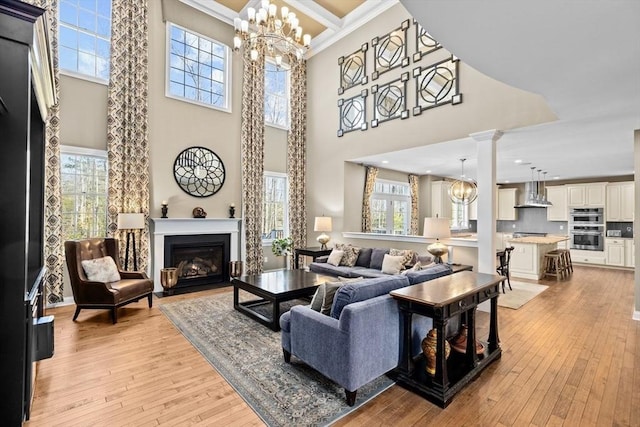 living room with an inviting chandelier, light wood-style flooring, and a fireplace with flush hearth