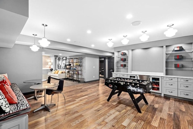 playroom with built in shelves, recessed lighting, light wood finished floors, baseboards, and a dry bar