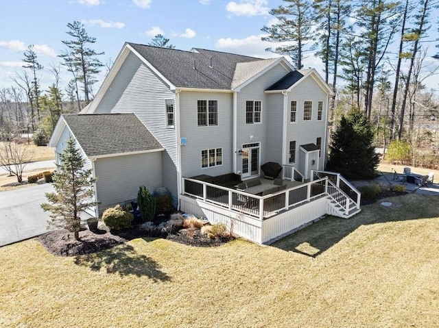 rear view of house featuring a yard, roof with shingles, and a wooden deck