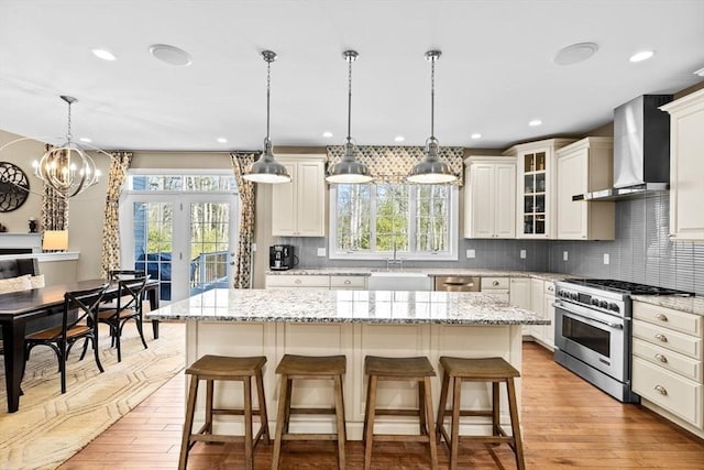 kitchen featuring a sink, a breakfast bar area, appliances with stainless steel finishes, and wall chimney exhaust hood