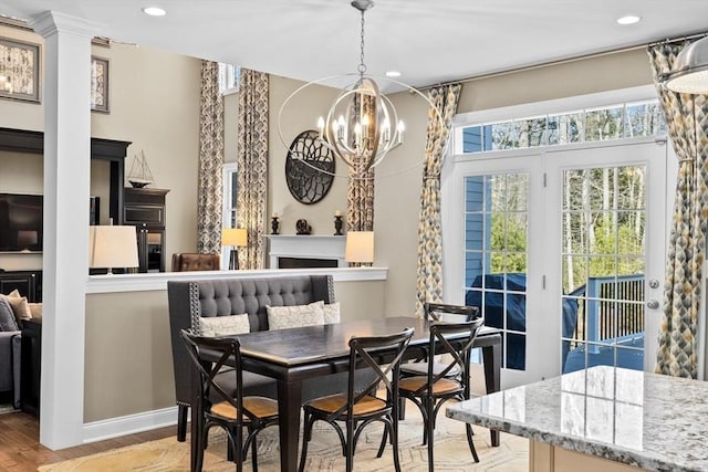 dining space featuring a chandelier, recessed lighting, a fireplace, and wood finished floors