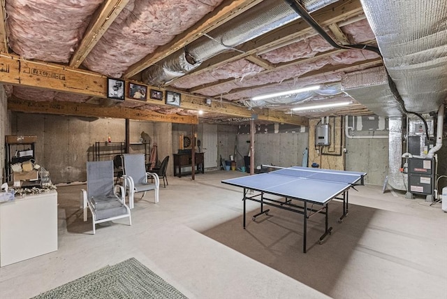 recreation room featuring water heater, concrete floors, and heating unit