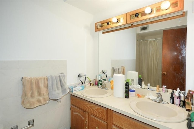 bathroom featuring a shower with shower curtain, double vanity, visible vents, and a sink