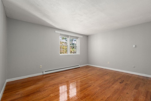 spare room with baseboards, a baseboard radiator, and wood finished floors