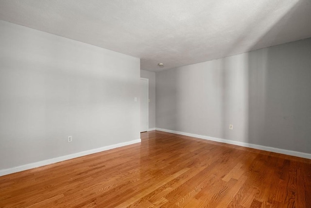 unfurnished room with baseboards and wood finished floors