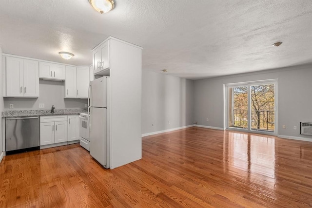 kitchen with white cabinets, light wood-style floors, white appliances, a textured ceiling, and open floor plan