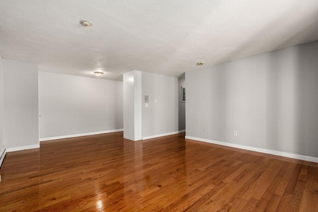 spare room with baseboards and wood finished floors