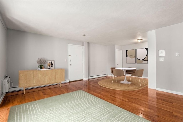 sitting room with wood finished floors, a baseboard radiator, baseboards, and a baseboard heating unit