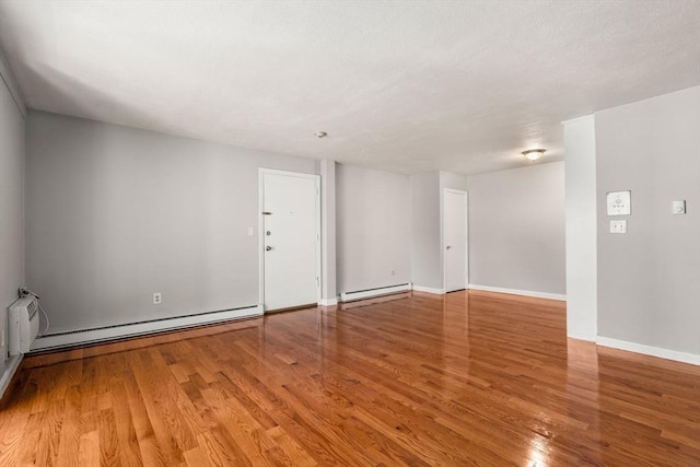 interior space featuring wood finished floors, baseboards, and a baseboard heating unit